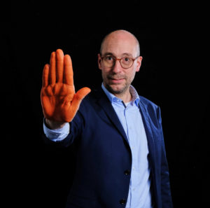 Ruppert Stüwe mit orange bemalter Hand zum Aktionstag gegen Gewalt gegen Frauen