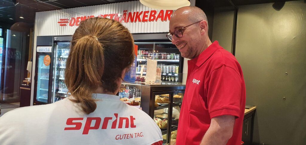 Ruppert Stüwe im Gespräch mit der Mitarbeiterin der Sprint-Tankstelle